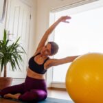 Nő pilates edzést végez egy sárga gimnasztikai labdával.